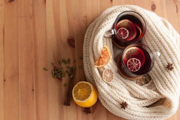 Seasonal and holidays concept . Christmas mulled wine with beautiful orange slices inside the glass , covered with warm white scarf . Very warm and cozy atmosphere