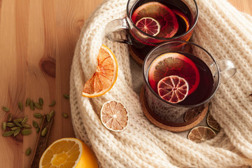 Seasonal and holidays concept . Christmas mulled wine with beautiful orange slices inside the glass , covered with warm white scarf . Very warm and cozy atmosphere