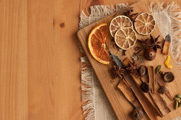 Cutting board with mixed spices and dry citrus slices on the linen tablecloth. On the wooden background . 