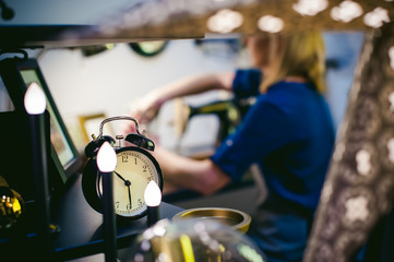 Obraz na płótnie Canvas round the clock on a blurred background. seamstress work on the sewing machine. young blond woman working on a mechanical sewing machine at home sitting at your desk, be prepared to sew