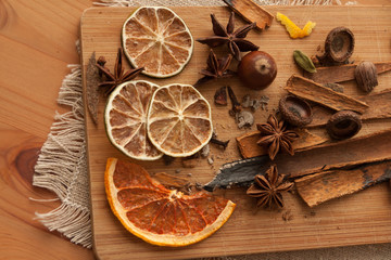 Cutting board with mixed spices and dry citrus slices on the linen tablecloth. On the wooden background . 