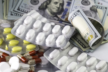 Hundred us dollar bills, medical sedative pills in blisters and digestive drugs,. US cash  money for the health care and purchase of pills and drugs. Horizontal close up image.