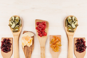 Assortment of dried fruits on wooden spoons on white background. Decorative border of dry exotic fruit. Top view.