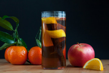 Glass with Seasonal warming drink.Cinnamon,lemon zest and some fruits.