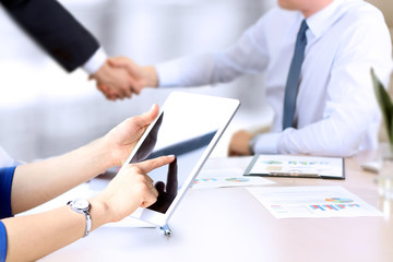 Image of business partners handshaking over business objects on