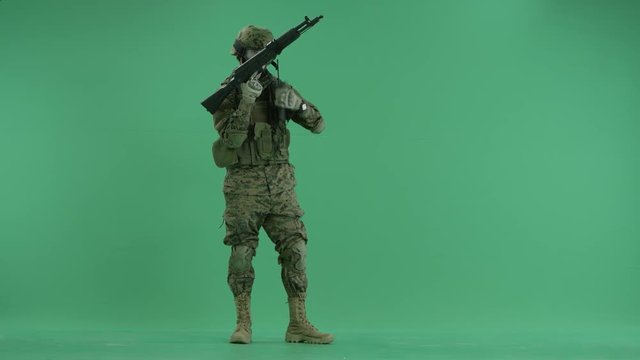 serviceman standing and targeting at camera at green screen