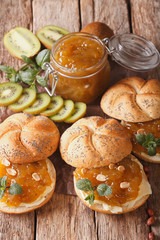 Tasty buns with butter and kiwi marmalade, mint and peanuts close-up. Vertical