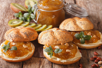 Delicious buns with butter, fruit jam kiwi, mint and peanuts close-up. Horizontal