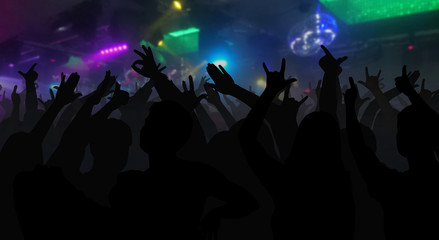 Fototapeta na wymiar Silhouettes of concert crowd with hands raised at a music disco