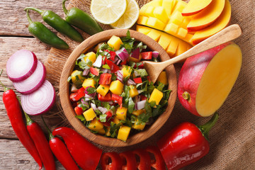 Salsa with mango, cilantro, onions and peppers close up and ingredients on the table. Horizontal...