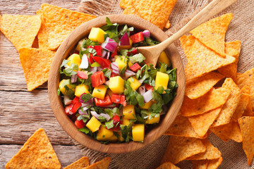 Mexican salsa with mango, peppers, cilantro and onion closeup and corn chips on the table. horizontal top view - obrazy, fototapety, plakaty