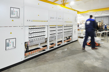 Worker in overalls carries the details along the rack of electri