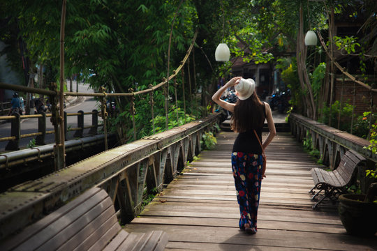 im girl walking on the old wooden bridge in Ubud, Bali.