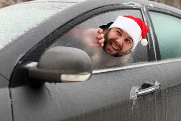 man in a red cap of Santa Claus in a car with broken glass
