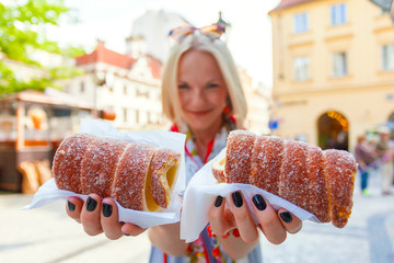 Young female tourist with traditional czech dessert called trdelnik in Prague. Czech Republic. Outdoor