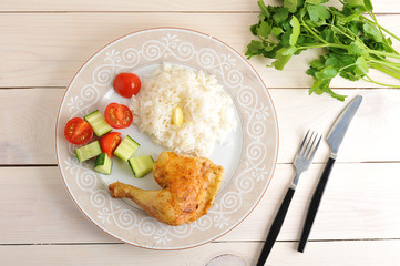 rice with roasted chicken leg and cucumber with tomatoes on plat