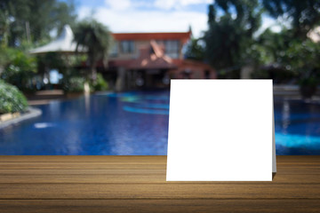 White card put on wooden desk or wooden floor on blurred swimming pool at resort background.use for present or mock up your product.product display template.Business presentation.clipping path include