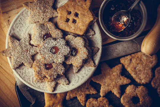 Homemade Christmas gingerbread and linzer cookies with jam, powdered, on baking sheet, top flat view, soft haze effect, vintage