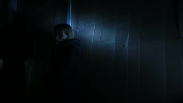 Scared woman hiding in a corner of an ancient building.