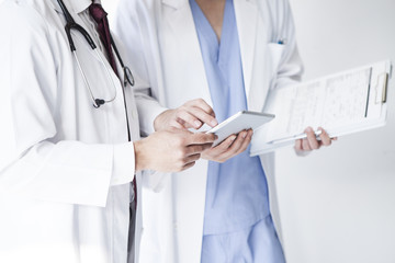 Doctors are talking while watching electronic tablets at a hospital
