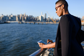 Young african fashionable businesswoman working outdoor, New York, Manhattan view, skyline
