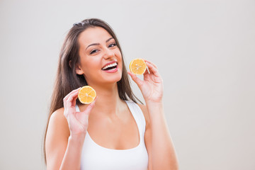 Beautiful young woman is holding lemon and smiling. 