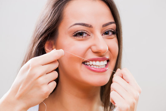 Close up image of young woman who is using dental floss.