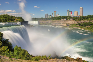 Rainbow at Niagara Falls with the skyline of the city of Niagara Falls in the background 