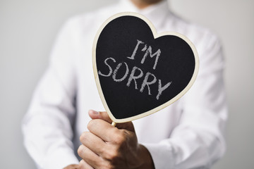 man with a signboard with the text I am sorry