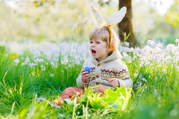 little kid boy having fun with traditional Easter egg hunt