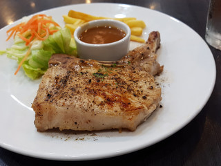 Grilled T-bone steak seasoned with spices pepper and fresh herbs