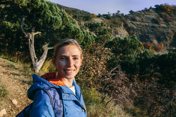 portrait of a beautiful young blonde woman outdoor on the background of mountain and forest