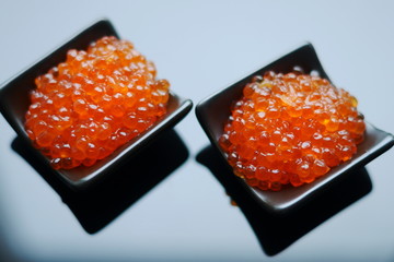 red caviar in black bowl on black glass background 