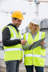 Woman in protective workwear and construction worker in construction site