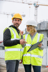 Woman in protective workwear and construction worker in construction site