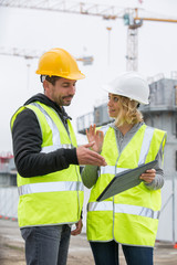 Woman in protective workwear and construction worker in construction site