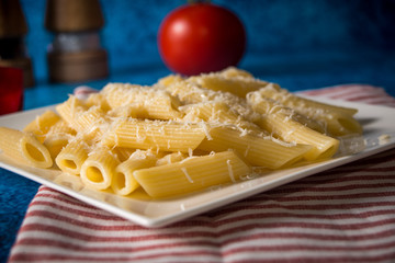 Penne pasta with parmesan cheese on a blue background