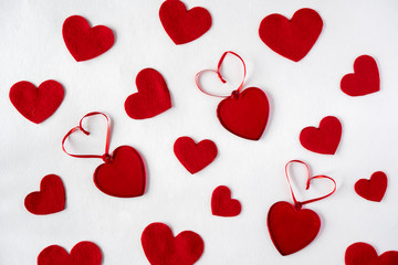 pattern of red felt and glass hearts on white desk 