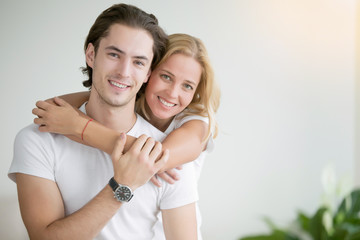 Young happy woman piggybacking her handsome boyfriend. Portrait of cheerful casual people in love, students having hopes, dreams, goals, bride and groom with family wants and aspirations
