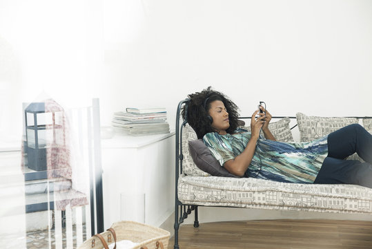 Woman text messaging while relaxing at home