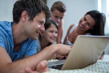 Fototapeta premium Happy family using laptop in bedroom