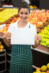 Obraz premium Smiling female staff holding a blank sheet at supermarket