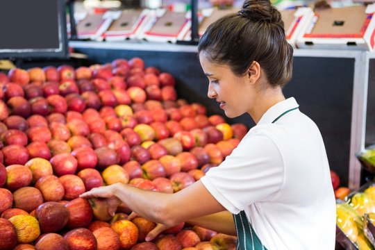 Female staff arranging fruits in organic section
