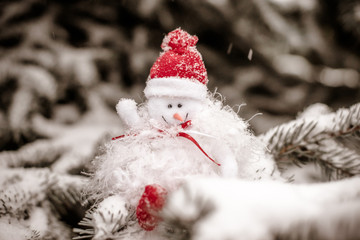 Christmas background Snowman sitting on snow-covered branches of a Christmas tree 