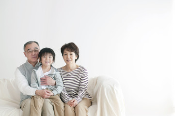 ソファーに座り微笑む孫と祖父母