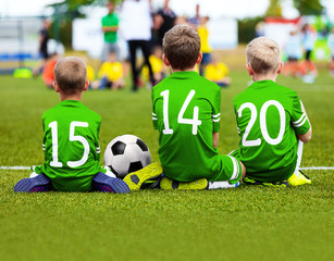 Children Soccer Team Playing Match. Football Game for Kids. Young Soccer Players Sitting on Pitch. Little Kids in Green Soccer Jersey Sportswear