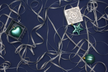 Fototapeta na wymiar Christmas a composition of boxes and toys turquoise, decorated with silver ribbon curls. New year decor on a dark blue background. Top view, flat lay