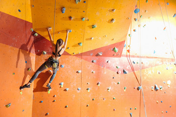 Slim woman climbing up special wall in gym