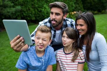 Happy family taking a selfie from digital tablet in park