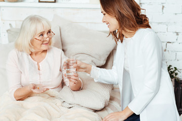 Obraz na płótnie Canvas Positive nurse visiting sick woman at home